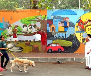 Mumbai : People Walk Past A Painted Wall Featuring The Theme Of Sparrow